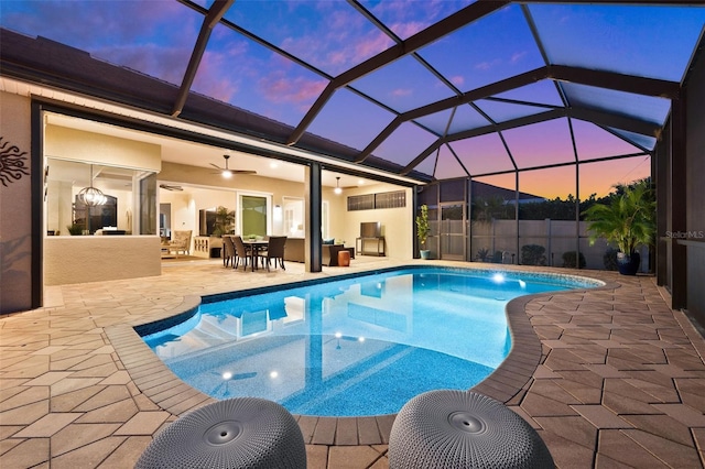 pool at dusk with a lanai, a patio area, and ceiling fan