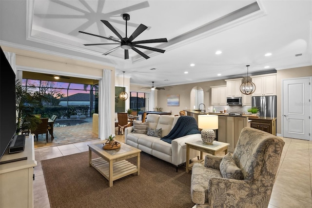 tiled living room featuring sink, ceiling fan, a raised ceiling, and crown molding