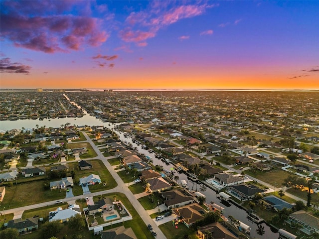 aerial view at dusk featuring a water view