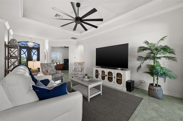 living room with a raised ceiling, ceiling fan, and ornamental molding