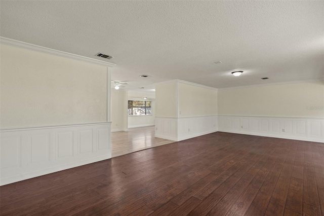 spare room featuring ornamental molding, visible vents, dark wood finished floors, and a textured ceiling