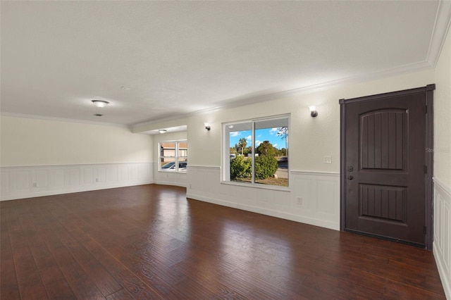 unfurnished living room featuring dark wood-style floors, ornamental molding, and wainscoting