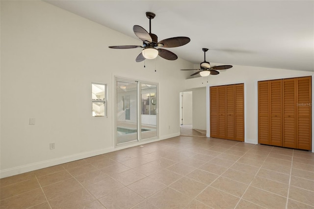 unfurnished bedroom with multiple closets, lofted ceiling, baseboards, and light tile patterned floors