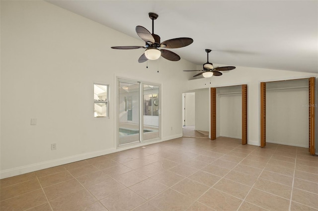 unfurnished bedroom with vaulted ceiling, light tile patterned flooring, two closets, and baseboards