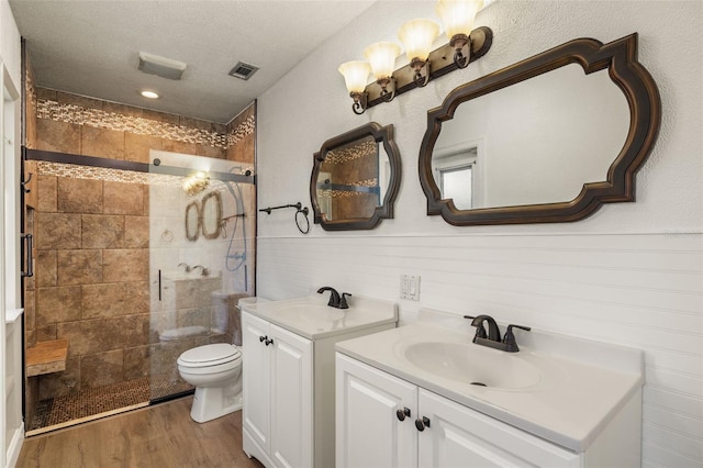 bathroom with visible vents, a tile shower, a sink, and wood finished floors