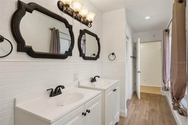 full bath with wood finished floors, two vanities, and a sink