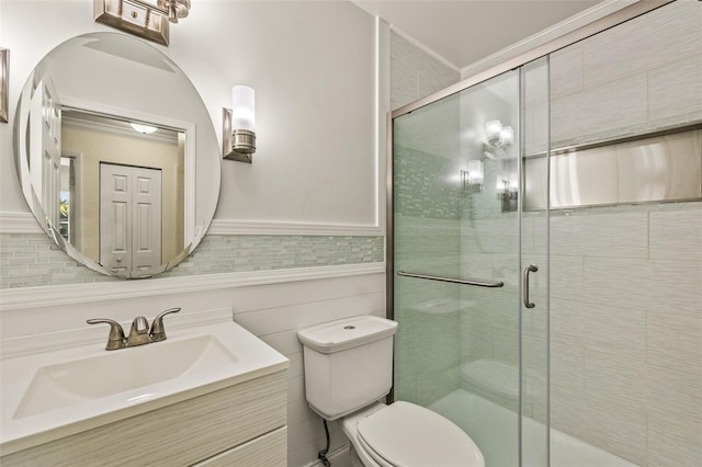 bathroom featuring a closet, wainscoting, toilet, and a stall shower