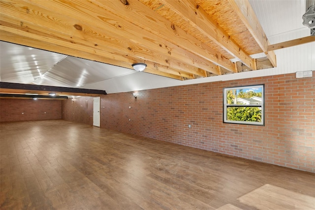 bonus room with beamed ceiling, brick wall, and wood finished floors