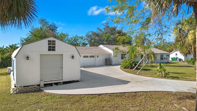 view of front of house featuring driveway, an attached garage, central AC unit, and a front lawn