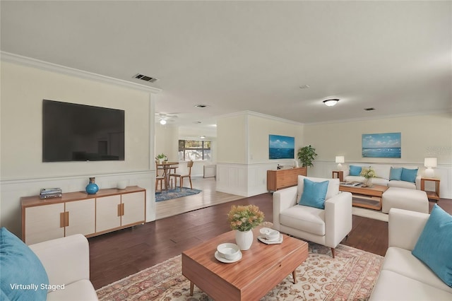 living room with wainscoting, visible vents, wood finished floors, and ornamental molding