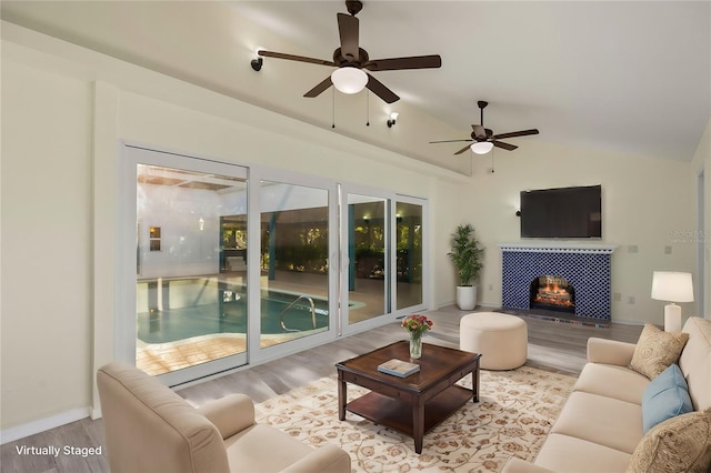 living room with lofted ceiling, ceiling fan, a fireplace, and light wood-style floors