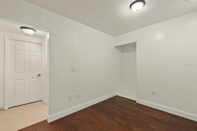 empty room with dark wood-style flooring and baseboards