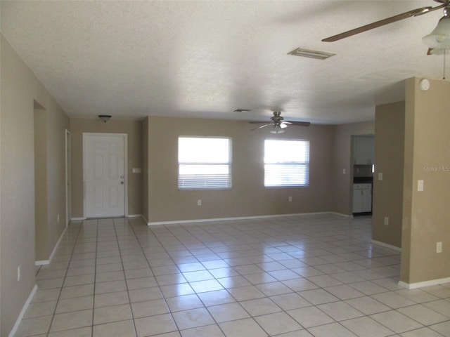 tiled empty room featuring a textured ceiling and ceiling fan