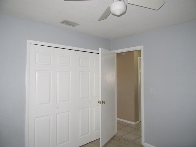 unfurnished bedroom featuring light tile patterned floors, a closet, and ceiling fan