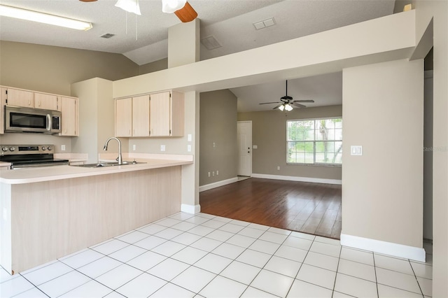 kitchen featuring lofted ceiling, sink, light hardwood / wood-style flooring, ceiling fan, and appliances with stainless steel finishes