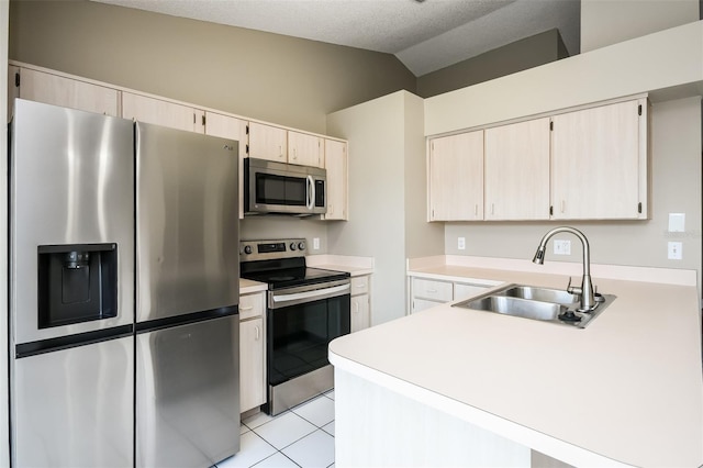 kitchen featuring lofted ceiling, sink, light tile patterned floors, a textured ceiling, and stainless steel appliances