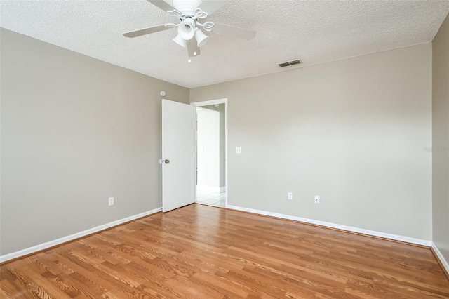 empty room featuring hardwood / wood-style floors, ceiling fan, and a textured ceiling