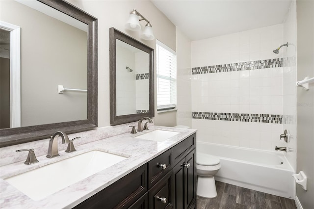 full bathroom featuring toilet, vanity, tiled shower / bath combo, and hardwood / wood-style flooring