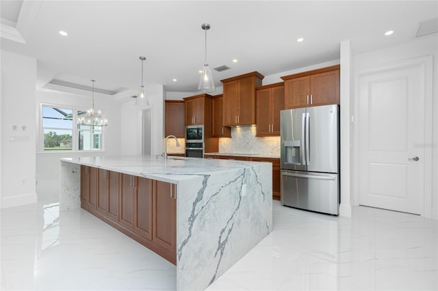 kitchen with hanging light fixtures, stainless steel appliances, light stone counters, decorative backsplash, and a large island with sink