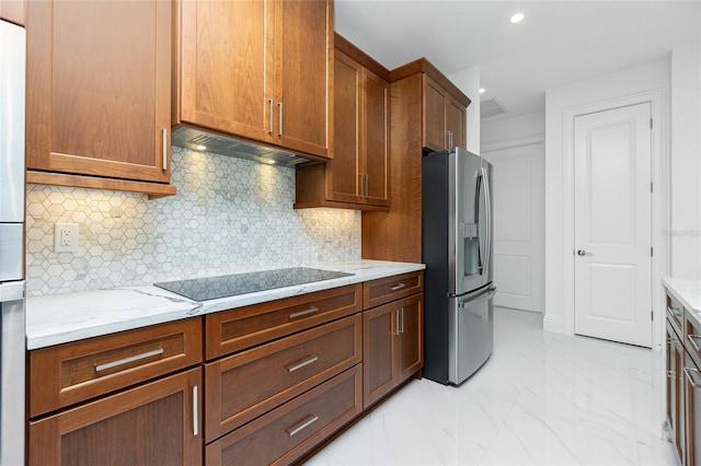 kitchen featuring backsplash, stainless steel fridge, exhaust hood, light stone countertops, and black electric cooktop