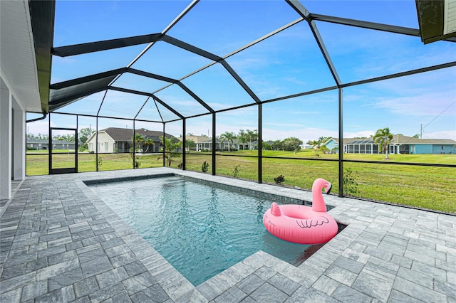 view of pool with a yard, a patio area, and glass enclosure