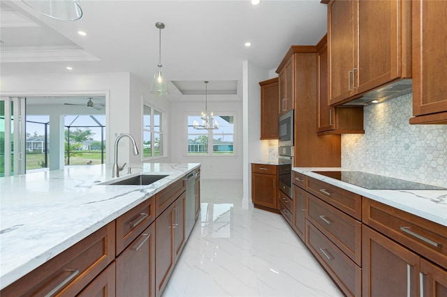 kitchen featuring tasteful backsplash, sink, light stone counters, and decorative light fixtures