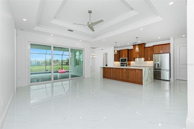 kitchen with tasteful backsplash, a tray ceiling, built in microwave, stainless steel fridge with ice dispenser, and decorative light fixtures