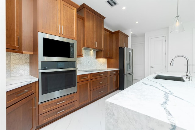 kitchen featuring stainless steel appliances, tasteful backsplash, sink, and light stone counters