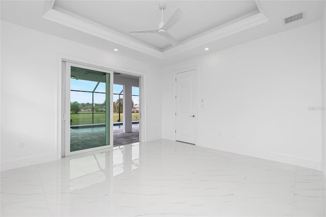 empty room featuring crown molding, ceiling fan, and a tray ceiling