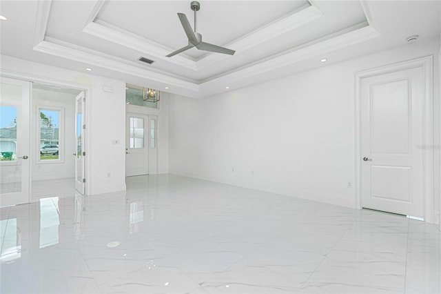 empty room with ornamental molding, a raised ceiling, ceiling fan, and french doors