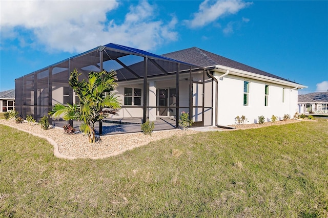 rear view of property featuring a yard, a patio area, and glass enclosure