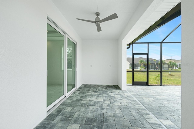 unfurnished sunroom featuring ceiling fan and a healthy amount of sunlight