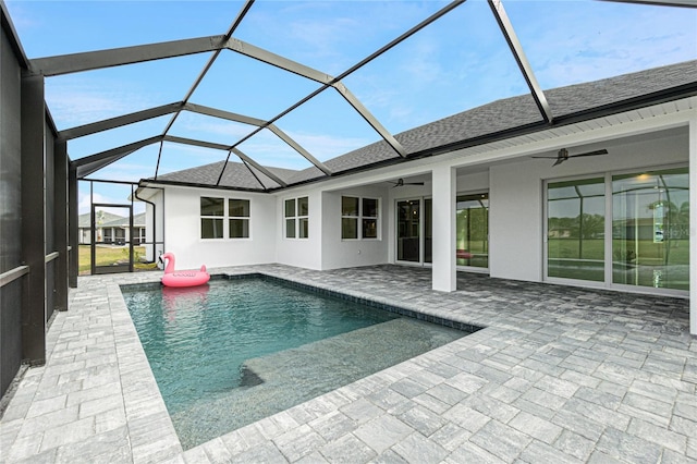 view of swimming pool featuring ceiling fan, glass enclosure, and a patio