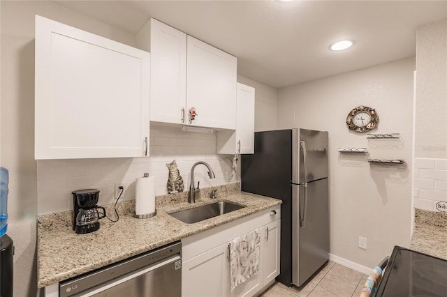 kitchen with decorative backsplash, appliances with stainless steel finishes, light stone counters, sink, and white cabinets