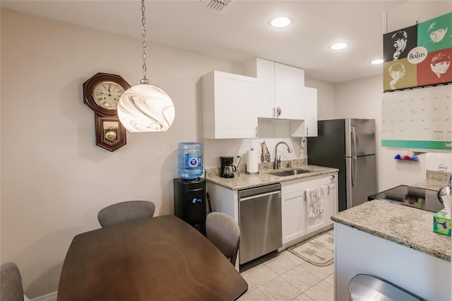 kitchen with light stone countertops, stainless steel appliances, sink, pendant lighting, and white cabinetry