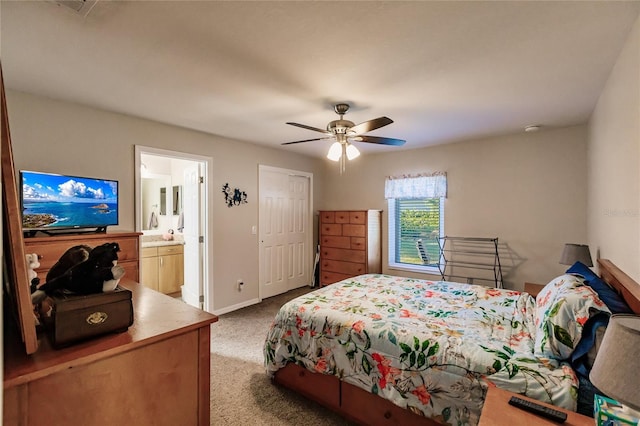 bedroom with a closet, light colored carpet, ensuite bath, and ceiling fan