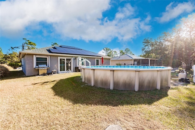 rear view of property with solar panels and a yard