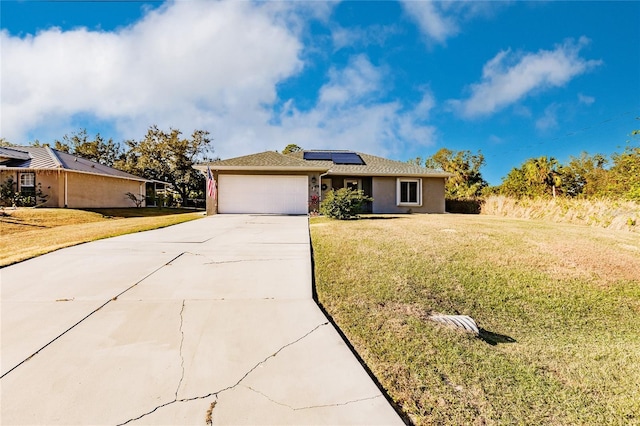 single story home with solar panels, a garage, and a front yard