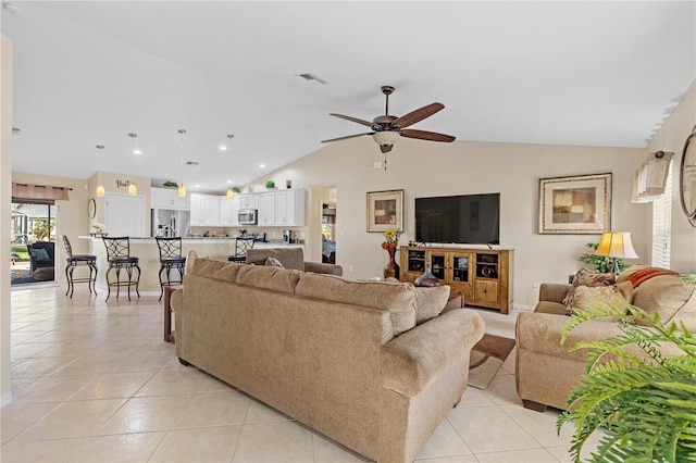 living room with ceiling fan, lofted ceiling, and light tile patterned flooring