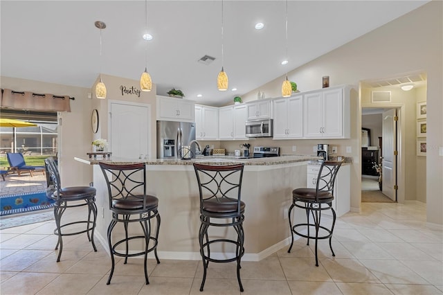 kitchen with white cabinetry, hanging light fixtures, stainless steel appliances, lofted ceiling, and a breakfast bar area