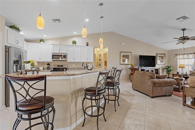 kitchen with white cabinets, lofted ceiling, stainless steel appliances, and hanging light fixtures