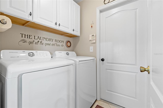 laundry area with washing machine and dryer, light tile patterned floors, and cabinets