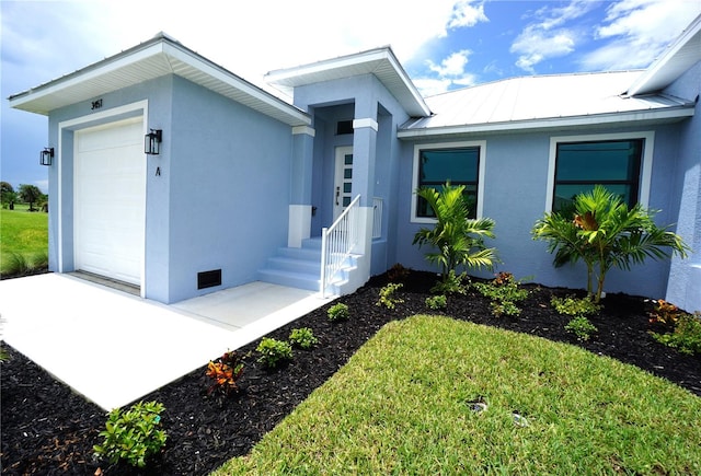 view of front of property featuring stucco siding, an attached garage, metal roof, and a standing seam roof