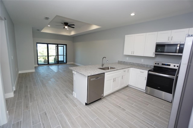 kitchen featuring kitchen peninsula, stainless steel appliances, sink, light hardwood / wood-style flooring, and white cabinets