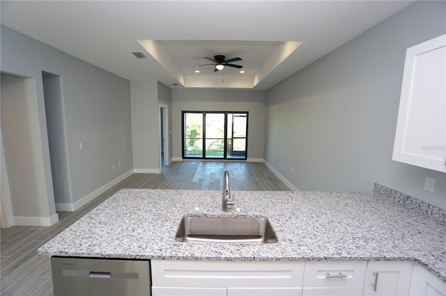 kitchen with stainless steel dishwasher, white cabinets, light stone countertops, and sink