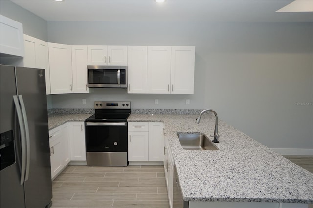 kitchen with white cabinetry, a peninsula, stainless steel appliances, and a sink