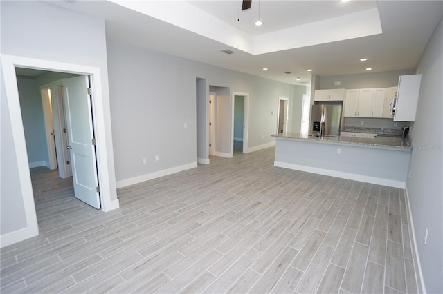 kitchen with white cabinets, appliances with stainless steel finishes, a tray ceiling, and wood finish floors