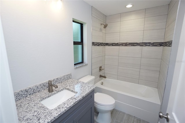 full bathroom featuring vanity, tiled shower / bath, and toilet