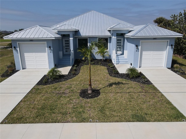 ranch-style house featuring an attached garage, metal roof, and stucco siding