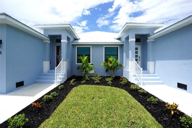 entrance to property featuring a standing seam roof, crawl space, metal roof, and stucco siding